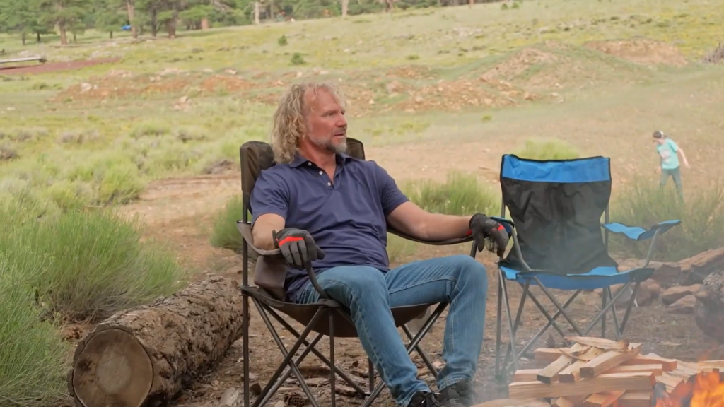 Kody Brown sits by an outdoor fire.