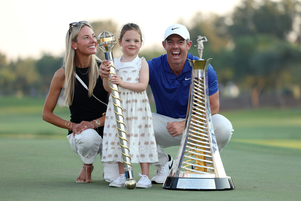 Rory McIlroy of Northern Ireland poses with his Wife, Erica Stoll and Daughter, Poppy McIlroy alongside the DP World Tour Championship trophy and the Race to Dubai trophy on the 18th green following victory on day four of the DP World Tour Championship 2024 at Jumeirah Golf Estates on November 17, 2024 in Dubai, United Arab Emirates. 