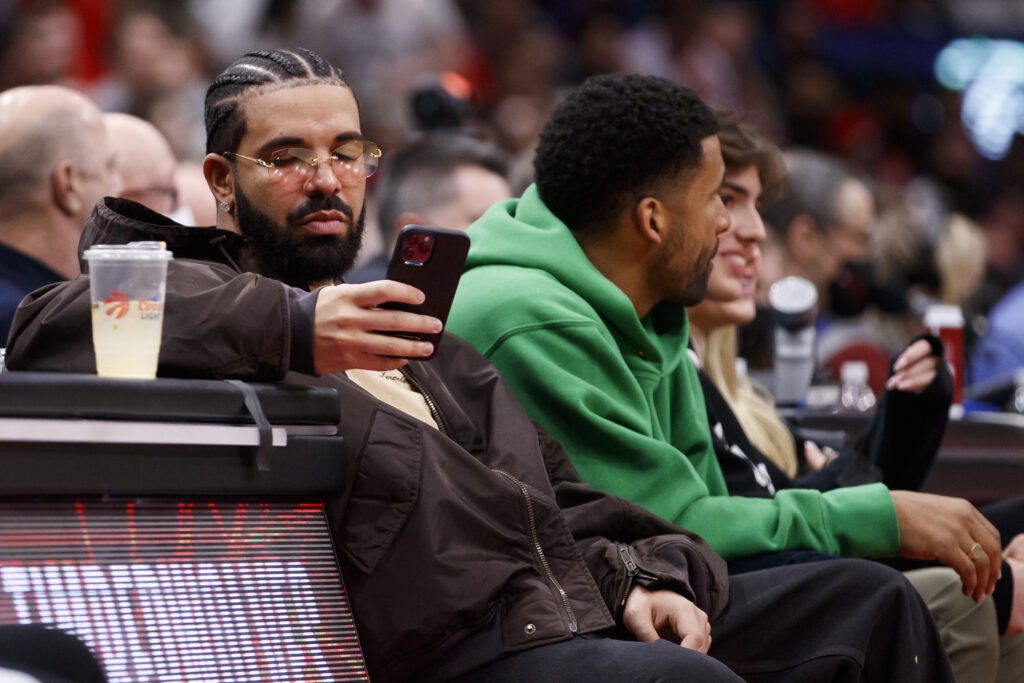 Drake texts while watching Game Six of the Eastern Conference First Round between the Toronto Raptors and the Philadelphia 76ers at Scotiabank Arena on April 28, 2022 in Toronto, Canada. 